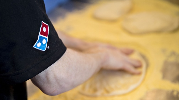 The Domino's Pizza Inc. logo is seen on a shirt as an employee prepares a customer's order at the company's restaurant in Chantilly, Virginia, U.S., on Tuesday, Feb. 20, 2018. Domino's released earnings figures on February 20. Photographer: Andrew Harrer/Bloomberg