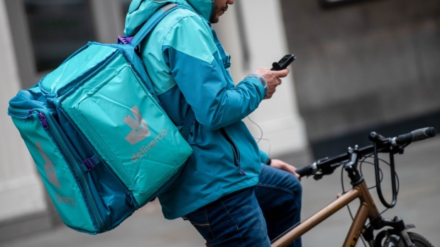 A food delivery courier for Deliveroo Holdings Plc looks at his phone in London, U.K., on Wednesday, March 31, 2021. Food-delivery startup Deliveroo Holdings Plc sank as much as 31% in its London debut after its initial public offering raised 1.5 billion pounds ($2.1 billion), putting pressure on the Citys efforts to boost its profile as a technology and listings hub post-Brexit. Photographer: Chris J. Ratcliffe/Bloomberg