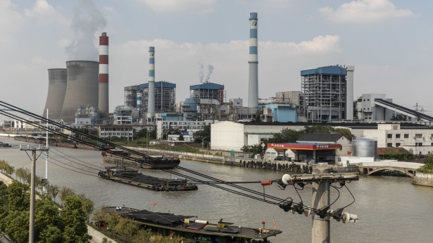 Barges travel past the Wangting Power Plant in Wangting, Jiangsu province, China, on Thursday, Sept. 30, 2021. China's central government officials ordered the country's top state-owned energy companies -- from coal to electricity and oil -- to secure supplies for this winter at all costs, according to people familiar with the matter.