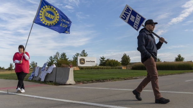 Deere & Co. workers hold signs during a strike outside the John Deere Des Moines Works facility in Ankeny, Iowa, U.S., on Friday, Oct. 15, 2021. Thousands of workers at Deere & Co., the world’s biggest farm machinery maker, began picketing Thursday for the first time in more than three decades to demand better pay as the company heads for its most profitable year ever.