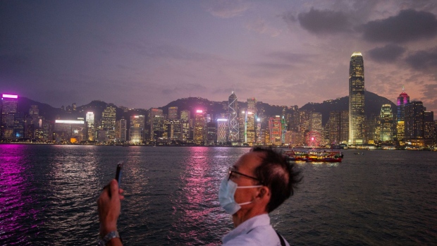 A man takes photographs of the city's skyline in the Tsim Sha Tsui area of Hong Kong, China on Friday, Oct. 29, 2021. Hong Kong is scheduled to release its third-quarter gross domestic product (GDP) figures on Nov. 1. Photographer: Billy H.C. Kwok/Bloomberg