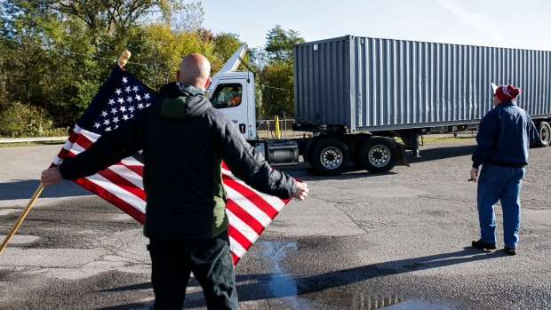 A demonstrator holds an American flag as a truck drives past during a union workers strike outside the Kellogg plant in Battle Creek, Michigan, U.S., on Friday, Oct. 22, 2021. Members of the Building and Construction Trades Council union will return to work Tuesday at the Kellogg Co. cereal factory in Omaha, Nebraska, while the broader strike against the company continues. Photographer: Jenifer Veloso/Bloomberg