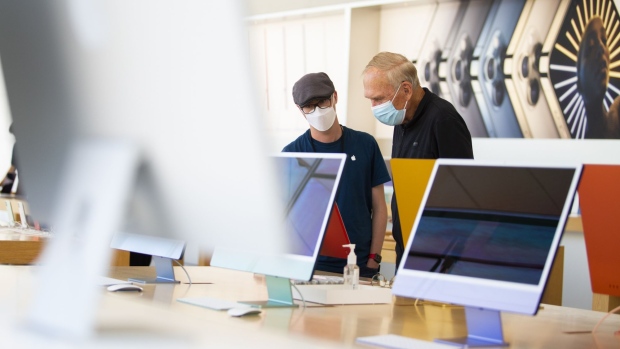 A customer wearing protective masks tries out the new Apple Inc. iMac computers at an Apple store in Palo Alto, California, U.S., on Friday, May 21, 2021. Apple Inc. rolled out the first redesign of its flagship desktop iMac computer in almost a decade, showcasing its latest machine with in-house designed chips instead of those made by Intel Corp. Photographer: Nina Riggio/Bloomberg