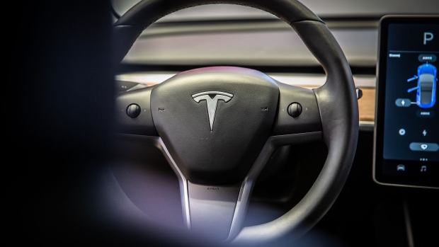 A sits on the steering wheel of a Tesla Inc. Model 3 electric vehicle