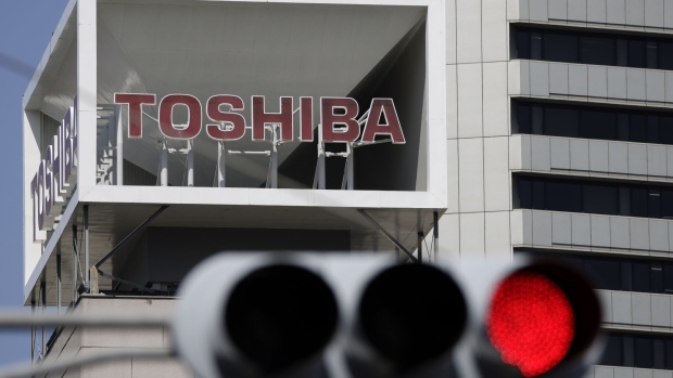 Signage for Toshiba Corp. displayed at the company's headquarters while a red traffic light is illuminated in Tokyo, Japan, on Wednesday, April 7, 2021. Toshiba surged its daily limit of 18% after confirming it received an initial buyout offer from CVC Capital Partners, setting the stage for potentially the largest private equity-led acquisition in years.