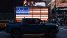 A Rivian R1T electric pickup truck drives past an illuminated U.S. flag during the company's IPO outside the Nasdaq MarketSite in New York, U.S., on Wednesday, Nov. 10, 2021. Electric vehicle-maker Rivian Automotive Inc. priced shares in its initial public offering at $78 apiece to raise about $11.9 billion, the biggest first-time share sale this year.