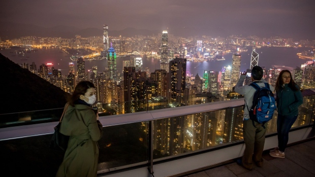 People look at the city's skyline from a viewing terrace at Victoria Peak in Hong Kong, China, on Monday, Feb. 3, 2020. The outlook for the Hong Kong economy in 2020 is “subject to high uncertainties” including the global economic recovery, U.S.-China trade relations, the ongoing protests and the progression of the viral outbreak, the government said in a release. Photographer: Paul Yeung/Bloomberg