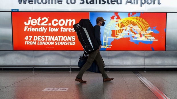 A passenger wearing a protective face mask passes an advertisement for Jet2 Plc at London Stansted Airport, operated by Manchester Airport Plc, in Stansted, U.K., on Monday, July 5, 2021. Jet2 will be making their next earnings announcement on July 8. Photographer: Chris Ratcliffe/Bloomberg