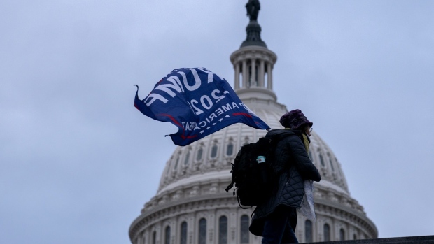 A demonstrator carries a "Trump 2020" flag outside the U.S. Capitol in Washington, D.C., U.S., on Wednesday, Jan. 6, 2021. The House and Senate will meet in a joint session today to count the Electoral College votes to confirm President-elect Joe Biden's victory, but not before a sizable group of Republican lawmakers object to the counting of several states' electors. Photographer: Stefani Reynolds/Bloomberg