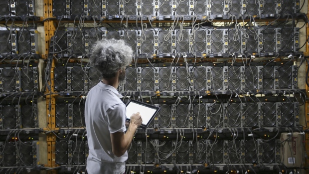 A worker inspects Bitcoin mining machines at a Canada Computational Unlimited Inc. computation center in Joliette, Quebec, Canada, on Friday, Sept. 10, 2021. CCU.ai, a Bitcoin mining center powered by hydroelectricity, has been conditionally approved for trading on the TSX Venture Exchange in Toronto under the stock symbol SATO. Photographer: Christinne Muschi/Bloomberg