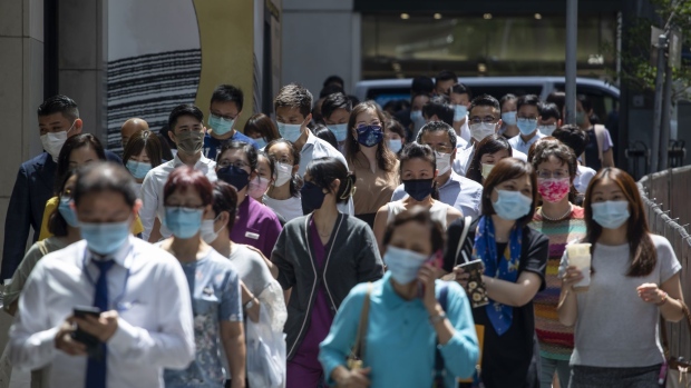 People wearing protective face masks walk along a street during lunch hour in Central district in Hong Kong, China, on Wednesday, Aug. 18, 2021. Hong Kong is caught between its desire to reopen and the government's zero tolerance for any cases of Covid-19, which has kept the virus out for most of the pandemic. Photographer: Paul Yeung/Bloomberg