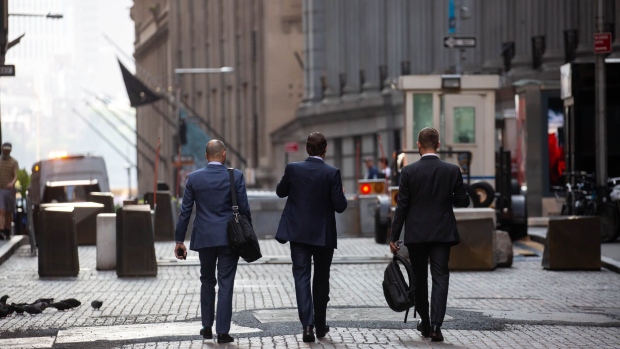 Pedestrians walk along Wall Street. Photographer: Michael Nagle/Bloomberg