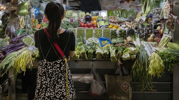 A shopper stands in front of a vegetable stall at Sanyuanli market in Beijing.