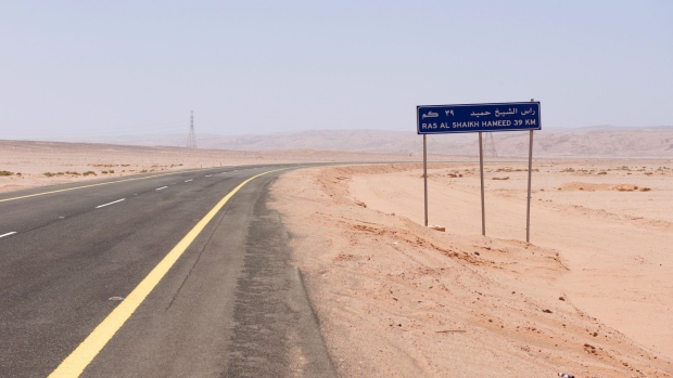 A road sign sits beside a desert highway indicating the distance to the bay at Ras Hameed, Saudi Arabia, on Friday, Feb. 26, 2016. It’s here that Saudi Arabia’s crown prince plans Neom, a city from scratch that will be bigger than Dubai and have more robots than humans. Photographer: Glen Carey/Bloomberg
