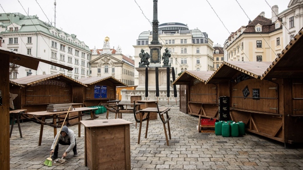 A worker sweeps around a closed Christmas market in central Vienna. Photographer: Akos Stiller/Bloomberg