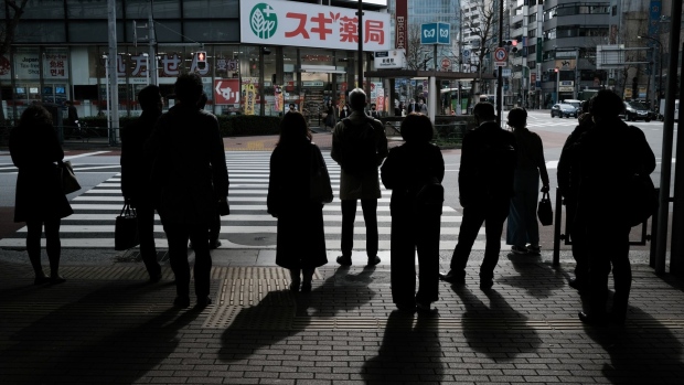 Pedestrians are silhouetted as they wait for traffic signals change in the Shimbashi District of Tokyo, Japan, on Monday, March 22, 2021. Japan ended the state of emergency in the Tokyo region Sunday, just days before the torch relay begins on March 25 for the virus-delayed Tokyo Olympics, now scheduled to start in July. Photographer: Soichiro Koriyama/Bloomberg