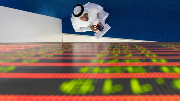 An investor looks up at a stock price index board during a visit to the Dubai Financial Market PJSC (DFM) in Dubai, United Arab Emirates, on Tuesday, March 10, 2020. The Middle Easts travel and business hub called on citizens and residents to avoid travel due to the coronavirus risk. Photographer: Christopher Pike/Bloomberg