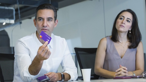 David Velez, founder and chief executive officer of Nubank, left, speaks while holding a credit card as Cristina Junqueira, co-founder and vice president of branding and business development at NuBank, listens during an interview in Sao Paulo in 2019.