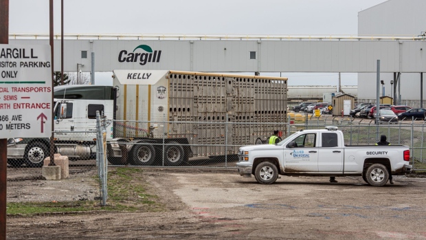 Workers wearing protective masks stand outside the Cargill Inc. beef plant in High River, Alberta, Canada, on Monday, May 4, 2020. The facility, which accounts for about 40% of Canada’s beef processing capacity, resumed work today despite the protests of the the union, which says the facility should remain closed until the company can ensure the safety of workers.