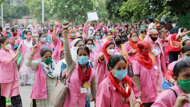 Workers with Accredited Social Health Activist (ASHA) from India's National Rural Health Mission wearing pink robes and protective masks, talk to a resident, left, as they conduct a door-to-door survey on the coronavirus in New Delhi, India, on July 2, 2020. India extended a scheme for distribution of free food grains to the country’s poorest until the end of November to help them cope with the economic pain of the country’s long drawn virus lockdown, Prime Minister Narendra Modi said.