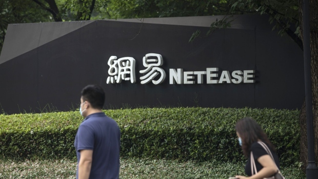 Pedestrians wearing protective masks walk past signage at the NetEase Inc. campus in Hangzhou, China, on Wednesday, June 10, 2020. NetEase Inc. soared more than 9% at the start of its first day of trading in Hong Kong on June 11, a solid debut that bodes well for a growing line-up of Chinese tech giants seeking to list closer to home.