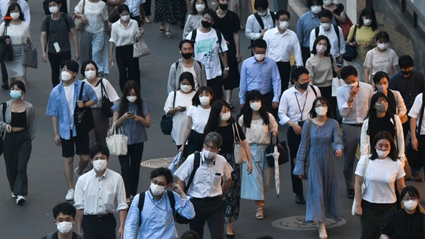 Evening commuters wearing protective face masks walk in the Shinjuku district of Tokyo, Japan, on Thursday, July 29, 2021. While the number of infections directly connected with the Olympics has so far been relatively low, Tokyo and its surrounding areas are experiencing their worst-yet virus wave. Photographer: Noriko Hayashi/Bloomberg