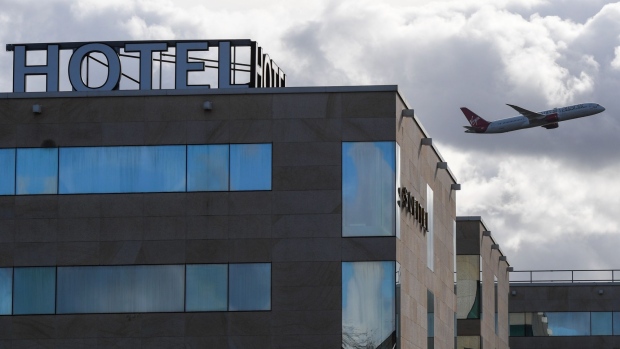 An aircraft flies over the Sofitel at London Heathrow Airport in London, U.K., on Monday, Feb. 15, 2021. Some passengers traveling to the U.K. will face tougher quarantine measures, including enforced stays in hotels, repeated tests, and the threat of fines and even jail.