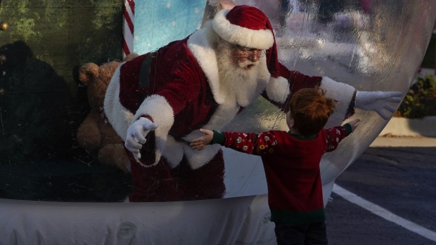 A performer dressed as Santa Claus greets a child from inside a big snow globe in Oklahoma City, Oklahoma, on Dec. 5, 2020. Photographer: Nick Oxford/Bloomberg