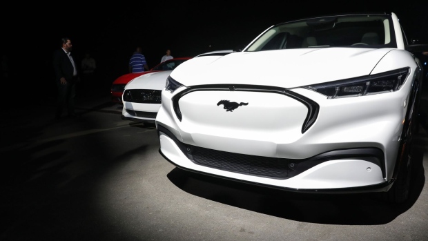 The Ford Motor Co. Mustang Mach-E electric sports utility vehicle (SUV) sits on display alongside other Mustang vehicles during a reveal event in Hawthorne, California, U.S., on Sunday, Nov. 17, 2019. Ford is reinventing one of its marquee models -- the Mustang muscle car -- as a battery-powered crossover to become a player in the electric-vehicle market that is expected to take off in the coming decade. Photographer: Patrick T. Fallon/Bloomberg