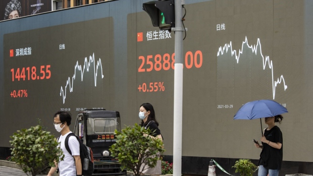 Pedestrians walk past a public screen displaying the Shenzhen Stock Exchange and the Hang Seng Index figures in Shanghai, China, on Wednesday, Aug. 18, 2021. President Xi Jinping said China must pursue "common prosperity," in which wealth is shared by all people, as a key feature of a modern economy, while also curbing financial risks. Photographer: Qilai Shen/Bloomberg