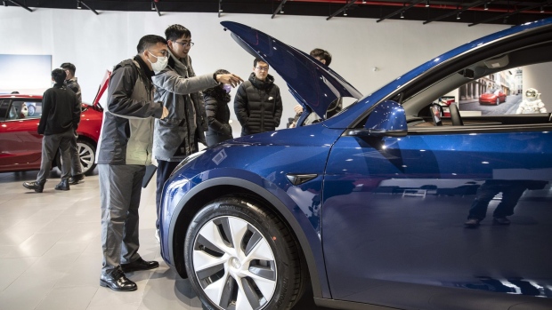Customers look at a Tesla Inc. Model Y electric vehicle at the automaker's showroom in Shanghai, China, on Friday, Jan. 8, 2021. Tesla customers in China wanting to get the new locally made Model Y are facing a longer wait, signaling strong initial demand for the Shanghai-built SUV.