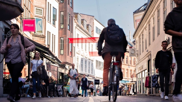 A cyclist and pedestrians make their way along a shopping street in Aalborg, Denmark, on Monday, Sept. 14, 2020. Denmark is re-introducing a number of coronavirus-related restrictions following the worst spike in infections since the height of the pandemic.