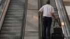 A pilot rides an escalator at Ben Gurion International airport in Tel Aviv, Israel, on Tuesday, Nov. 30, 2021. Israel is focused on rolling out vaccine booster shots and the country will need a few weeks to reconsider lifting a travel ban on incoming foreigners, the chairman of the country's Covid-19 advisory team said.