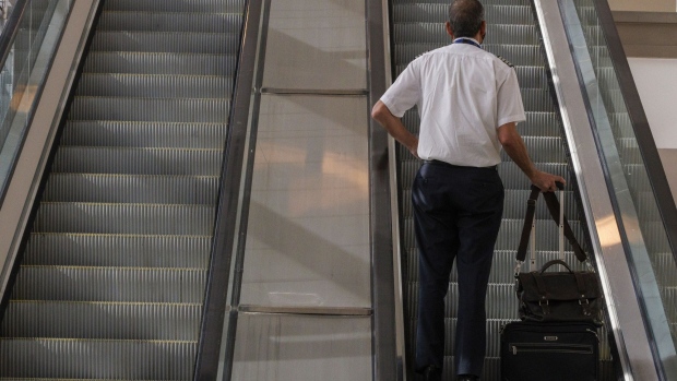 A pilot rides an escalator at Ben Gurion International airport in Tel Aviv, Israel, on Tuesday, Nov. 30, 2021. Israel is focused on rolling out vaccine booster shots and the country will need a few weeks to reconsider lifting a travel ban on incoming foreigners, the chairman of the country's Covid-19 advisory team said.