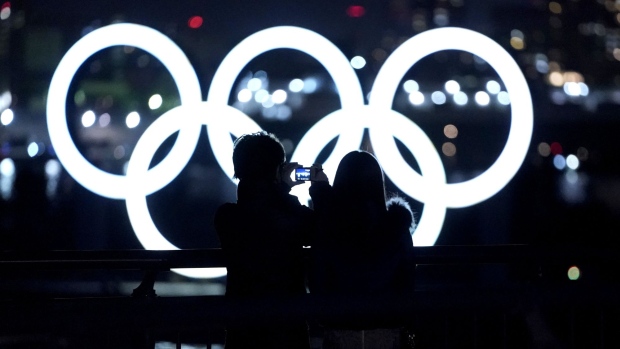 A visitor takes a photograph of illuminated Olympic rings floating in the waters off Odaiba island in Tokyo, Japan, on Thursday, Jan. 14, 2021. While Japan’s infection count has been well below other rich industrialized nations, the pandemic has been a persistent cloud over the Olympics since they were delayed almost a year ago. Photographer: Toru Hanai/Bloomberg