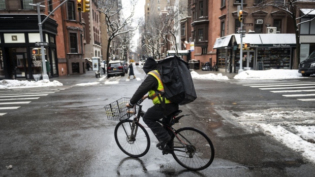 A food delivery worker rides a bicycle during a winter storm in New York, U.S., on Friday, Feb. 19, 2021. A meandering storm will leave New York and the Northeast with up to 8 inches (20 centimeters) of snow through Friday, while ice and cold continue to plague Texas.