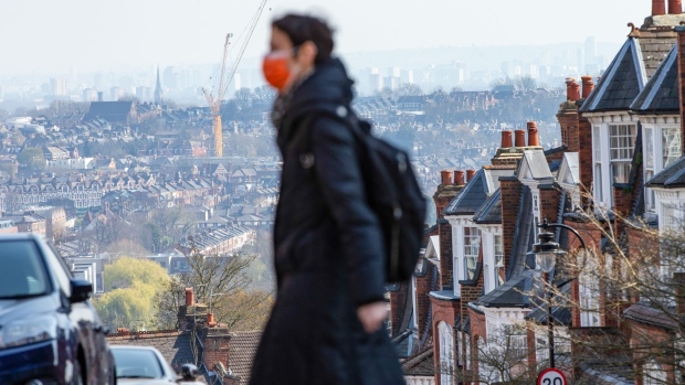 A pedestrian wearing a protective face mask walks past residential properties in London, U.K., on Friday, March 27, 2020. U.K. house sales are set to plunge by 60% in the next three months as the coronavirus outbreak batters the economy.