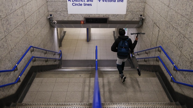 A commuter carries a scooter at London Victoria railway station, during a strike by London Underground drivers, in London, U.K., on Friday, Nov. 26, 2021. Drivers for London's underground rail network said they will strike on Friday after failing to resolve a scheduling dispute over the restoration of overnight services. Photographer: Hollie Adams/Bloomberg