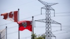 Canadian and Ontario flags fly in front of a Hydro One Ltd. transmission tower in Toronto, Ontario, Canada, on Thursday, July 12, 2018. Hydro One is facing a long-term share overhang after new Ontario Premier Doug Ford fulfilled an election promise to oust the utility's chief executive offer and board of directors, analysts say.