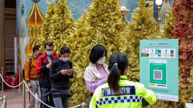 Visitors wait in line to scan a QR code for the LeaveHomeSafe Covid-19 contact-tracing app in front of Christmas trees in Hong Kong, China, on Tuesday, Dec. 7, 2021. Hong Kong will prioritize quarantine-free travel for business people when its China border reopens, Chief Executive Carrie Lam said, warning that the city’s vaccination rate could curb a broader roll-out. Photographer: Paul Yeung/Bloomberg