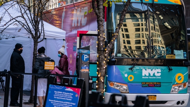 Pedestrians wait in line at a Covid-19 mobile vaccine bus near Central Park in New York, U.S., on Sunday, Dec. 5, 2021. Five months after President Joe Biden declared the U.S. to be on the verge of defeating Covid-19, the virus threatens a winter resurgence across the country with the omicron variant threatening to fuel an already high case count.