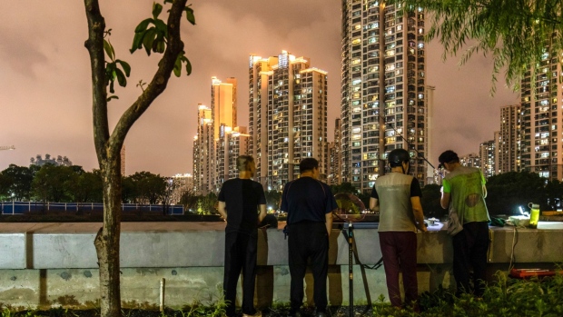 Men fish near a large residential compound in Shanghai, China, on Wednesday, Sept. 29, 2021. The National Development and Reform Commission will let power prices reasonably reflect changes in demand, supply and costs, it said in a statement on measures to ensure power supply through winter and spring seasons. Photographer: Qilai Shen/Bloomberg
