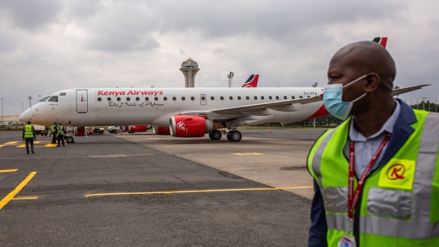 A member of ground crew for Kenya Airways Ltd. wears a protective face mask as he stands in front of an Embraer SA 190 passenger aircraft, operated by Kenya Airways Ltd., on the tarmac during a reopening ceremony at Jomo Kenyatta International Airport in Nairobi, Kenya, on Wednesday, July 15, 2020. Kenya Airways Plc started a three-month round of job cuts as lawmakers debate a bill to nationalize the carrier and its losses mount due to the impact of the coronavirus pandemic.