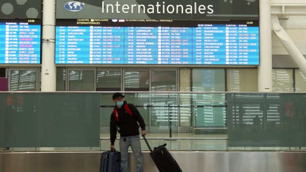 A traveler stands under a flight info board at Pearson International Airport in Toronto, on Dec. 27.
