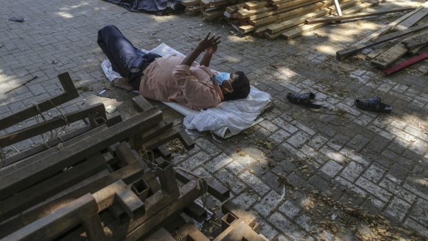 A worker uses a smartphone while taking a break at the construction site of a 400 bed non-critical hospital for Covid-19 treatment in the parking lot of the Mahalaxmi Race Course in Mumbai, India, on Friday, May 8, 2020. The economic crisis looks set to be one of Modi's most serious challenges since he swept to power in 2014, with fears the nation could be heading for its first full-year contraction in more than four decades. Photographer: Dhiraj Singh/Bloomberg