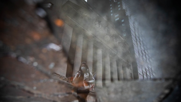 A pedestrian reflected in a puddle outside the New York Stock Exchange (NYSE) in New York, U.S., on Friday, Dec. 31, 2021. U.S. stocks swung between gains and losses, with moves exacerbated by thin trading on the last session of the year.