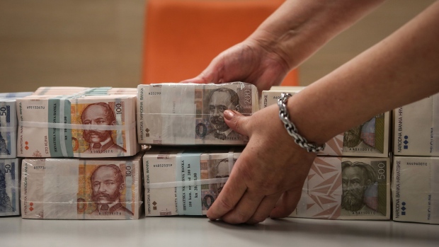 An employee places bundles of Croatian kuna banknotes on a table in this arranged photograph at the Croatian Central Bank in Zagreb, Croatia, on Thursday, Aug. 20, 2020. The Adriatic nation and Bulgaria got the green light to join the pre-euro currency system last month, and now have at least two more years to prove they can comfortably meet membership requirements before making the switch. Photographer: Oliver Bunic/Bloomberg