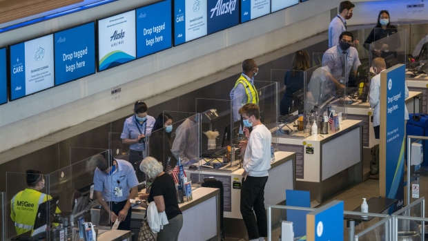 Travelers wearing protective masks check-in for flights at an Alaska Airlines Inc. check-in area at San Francisco International Airport in San Francisco, California, U.S., on Monday, Oct. 19, 2020. Alaska Airlines is expected to release earnings figures on Oct. 22.