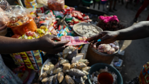 A customer pays with a Ghana cedi banknote at a food market in Accra, Republic of Ghana, on Wednesday, Nov. 3, 2021. Ghana’s inflation rate breached the central bank’s target band in September after supply bottlenecks, a weak cedi and surging energy costs propelled food-price growth to a seven-month high.