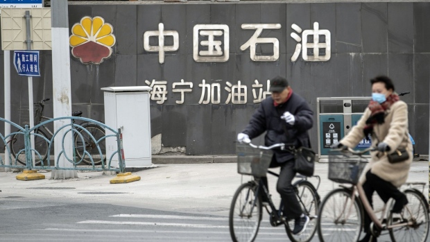 Cyclists ride past a PetroChina Co. gas station in Shanghai. Photographer: Qilai Shen/Bloomberg